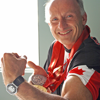 Sylvio Bourque smiling in a Team Canada jersey with medals